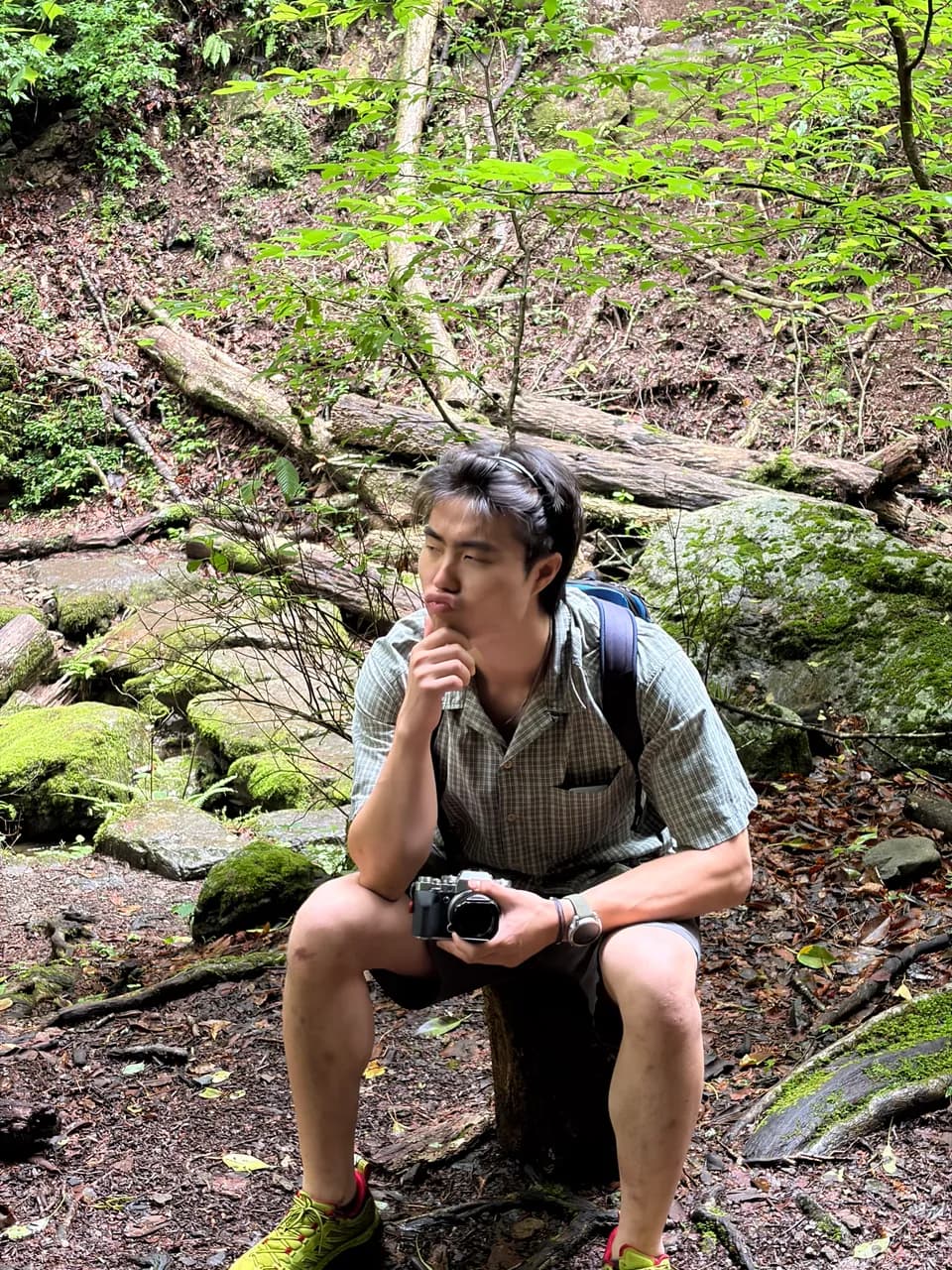 Zach sitting in a forest with a camera
